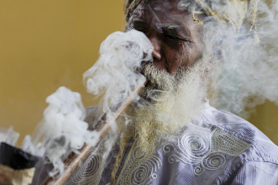 Ras Jah, a member of the Ras Freeman Foundation for the Unification of Rastafari, smokes cannabis from a chalice pipe during service in the tabernacle on Sunday, May 14, 2023, in Liberta, Antigua. For Rastafari, the practice of smoking the herb brings them closer to the divine. But for decades, many have been jailed and endured racial and religious profiling by law enforcement because of their marijuana use. (AP Photo/Jessie Wardarski)