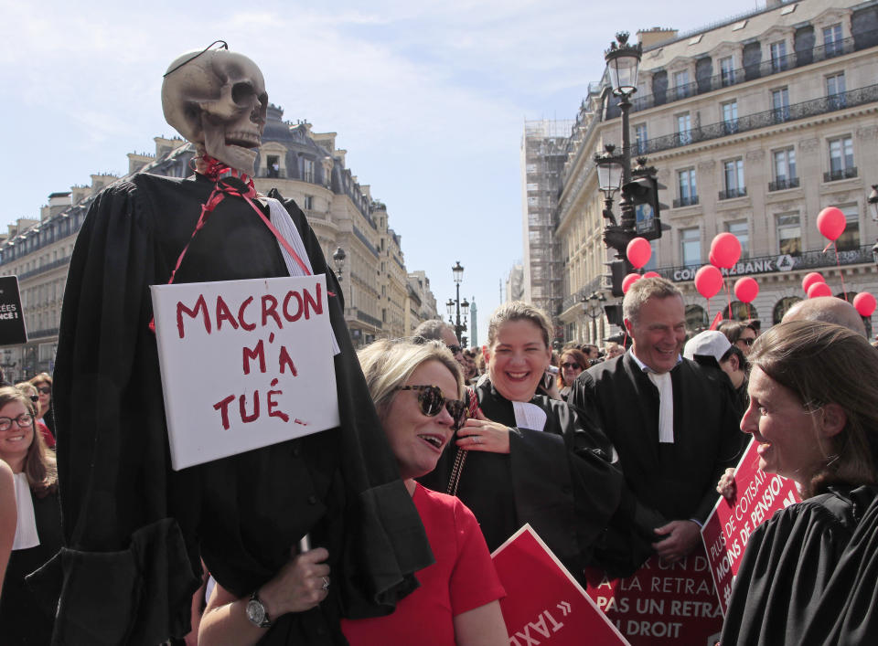 A lawyer holds a effigy with a scull represending a dead lawyer march during a protest against the planned pension change in Paris, Monday, Sept. 16, 2019. French lawyers, doctors, nurses, pilots and others are taking to the streets of Paris to protest planned pension changes by French President Emmanuel Macron's government. Placard read, "no to the pension tax". Placard reads, "Macron wants my dead". (AP Photo/Michel Euler)