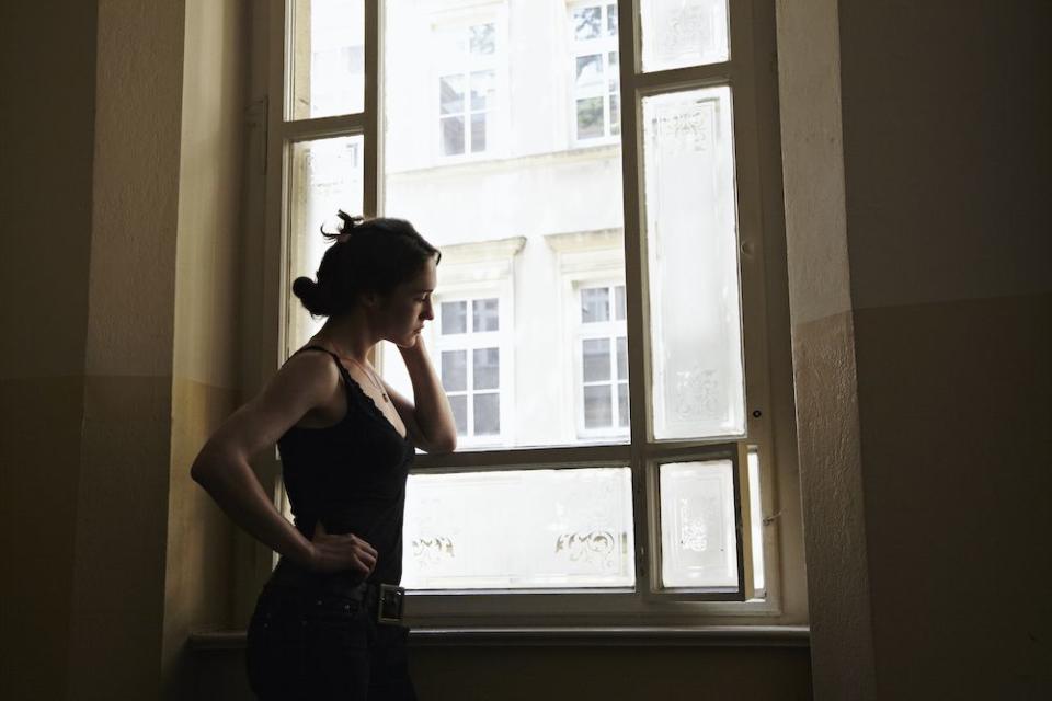 morning anxiety young woman standing in a stairway looking outside the window