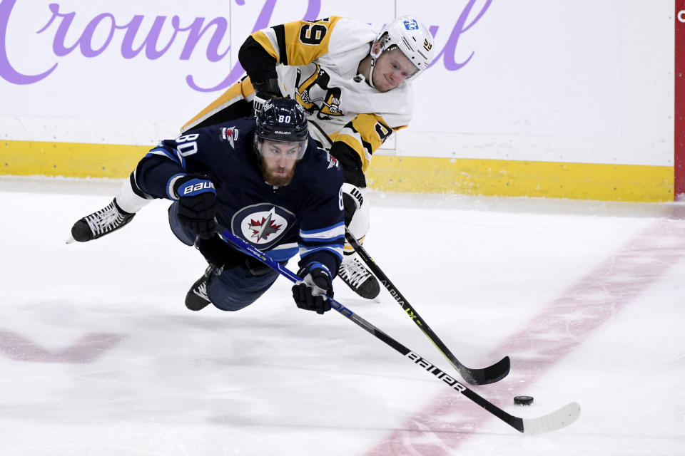 Winnipeg Jets' Pierre-Luc Dubois (80) and Pittsburgh Penguins' Jake Guentzel (59) vie for the puck during the first period of an NHL hockey game Monday, Nov. 22, 2021, in Winnipeg, Manitoba. (Fred Greenslade/The Canadian Press via AP)