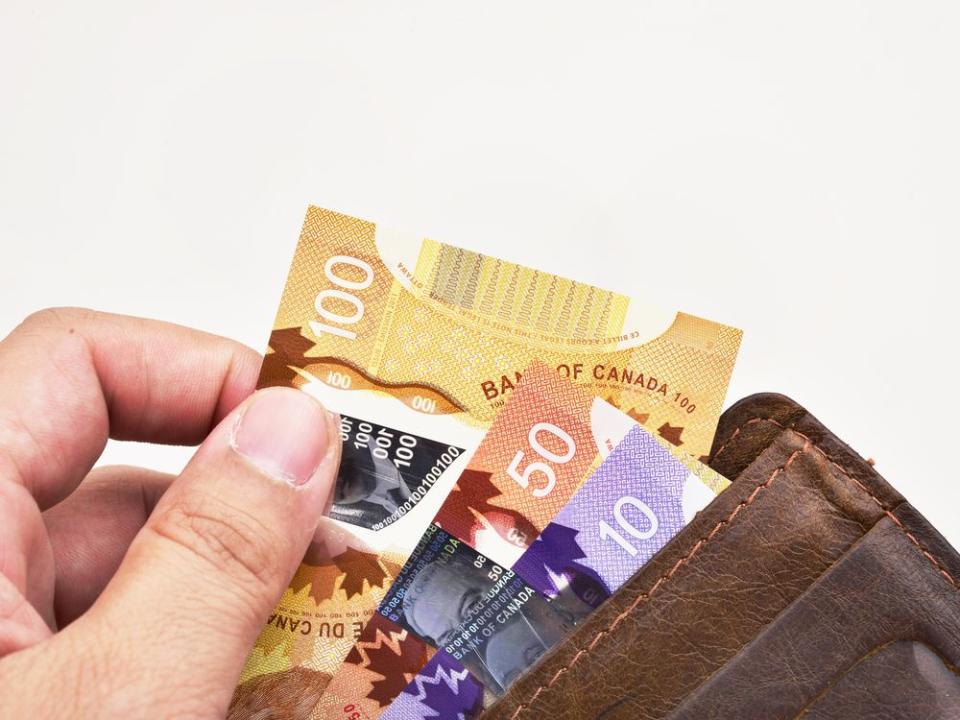 Hand holding one hundred Canadian banknotes (CAD)