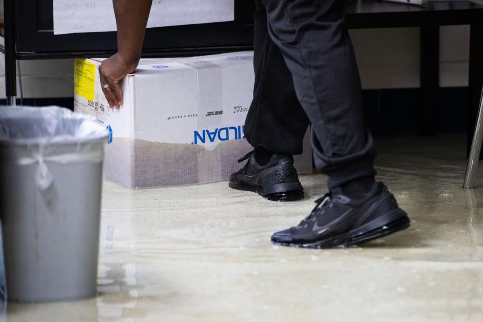 A Godby High School teacher removes damaged items from a classroom after the school experienced flooding overnight from torrential rain Thursday, April 11, 2024.