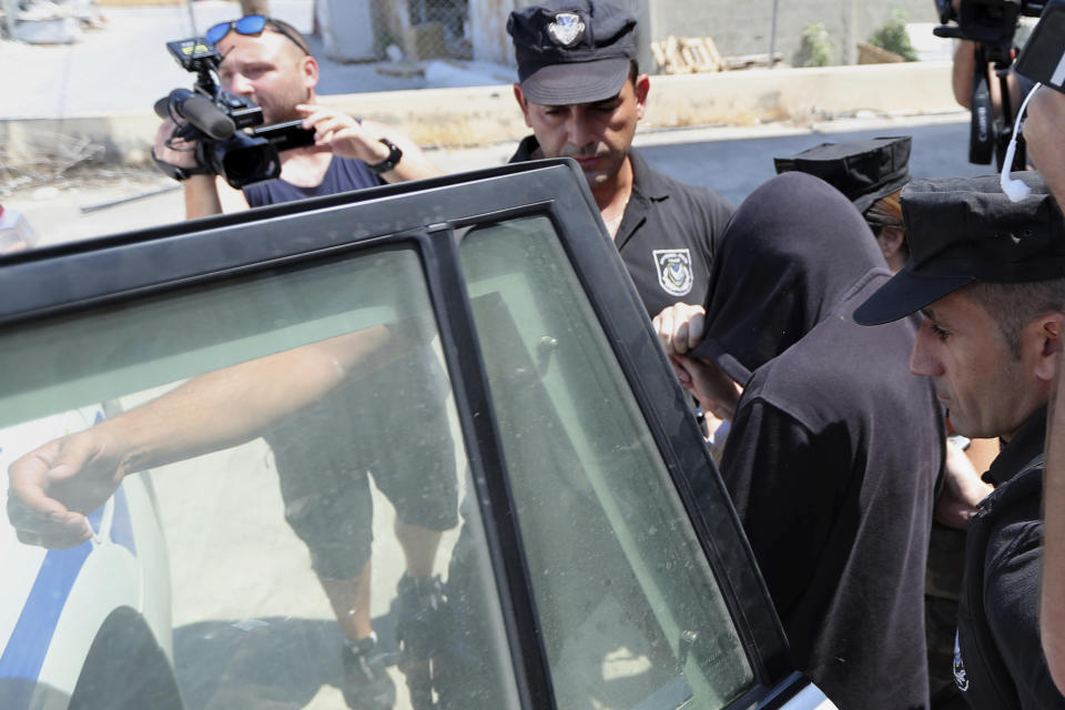 Elite police unit officers escort a 19-year old British woman, with head covered, from the Famagusta court in Paralimni, Cyprus, Tuesday, July 30, 2019, after her case was postponed. The British woman faces a public nuisance charge after she admitted that her accusation that 12 Israeli teens raped her at a popular resort town was untrue. (AP Photo/Petros Karadjias)