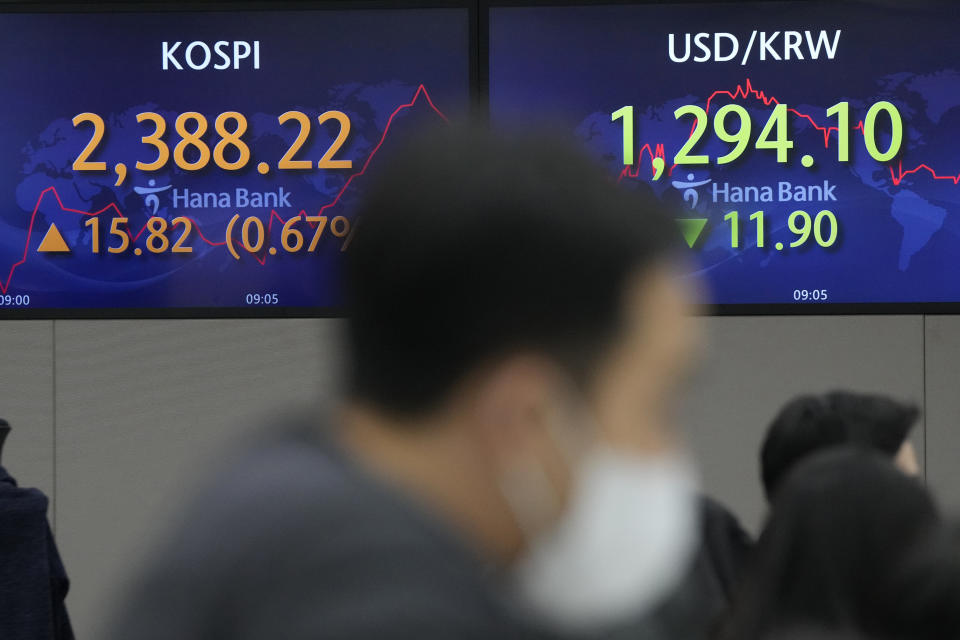 A currency trader works near screens showing the Korea Composite Stock Price Index (KOSPI), left, and the foreign exchange rate between the U.S. dollar and South Korean won at the foreign exchange dealing room of the KEB Hana Bank headquarters in Seoul, South Korea, Wednesday, Dec. 14, 2022. Stocks rose Wednesday in Asia after a rally on Wall Street spurred by news that inflation in the U.S. cooled more than expected last month. (AP Photo/Ahn Young-joon)