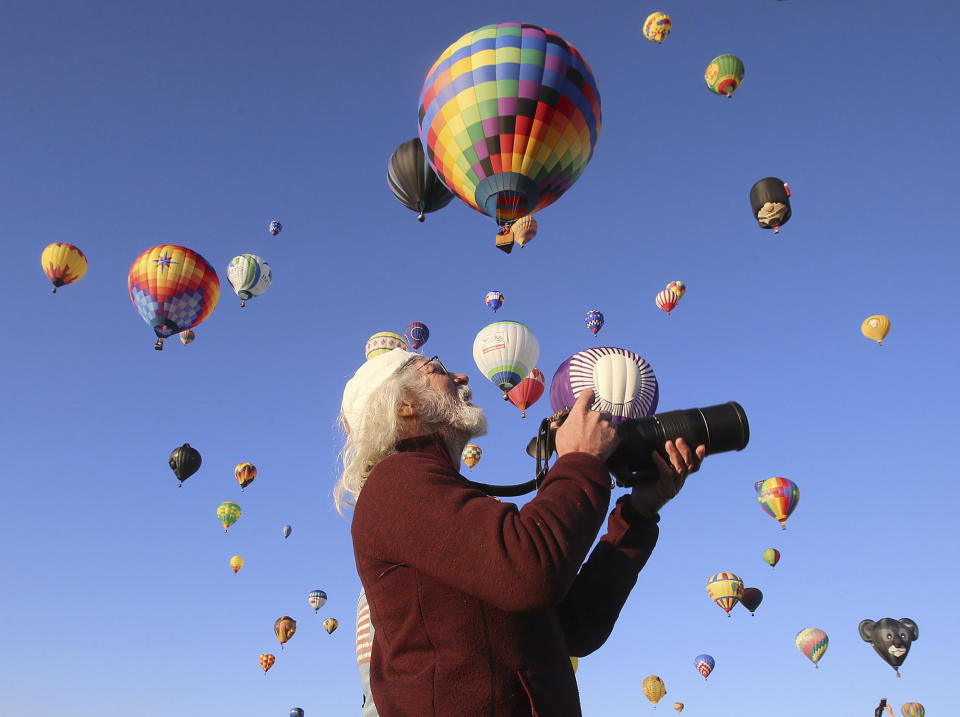 A balloon enthusiasts takes photos of the balloons as they lift-off at the Albuquerque International Balloon Fiesta Sunday, Oct. 6, 2019, in Albuquerque, N.M. (Jerry Larson/Waco Tribune-Herald via AP)