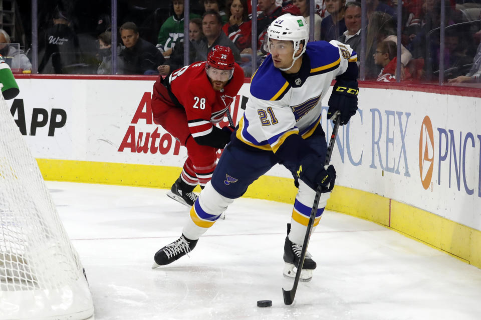 St. Louis Blues' Tyler Bozak (21) moves the puck away from Carolina Hurricanes' Ian Cole (28) during the third period of an NHL hockey game in Raleigh, N.C., Saturday, Nov. 13, 2021. (AP Photo/Karl B DeBlaker)
