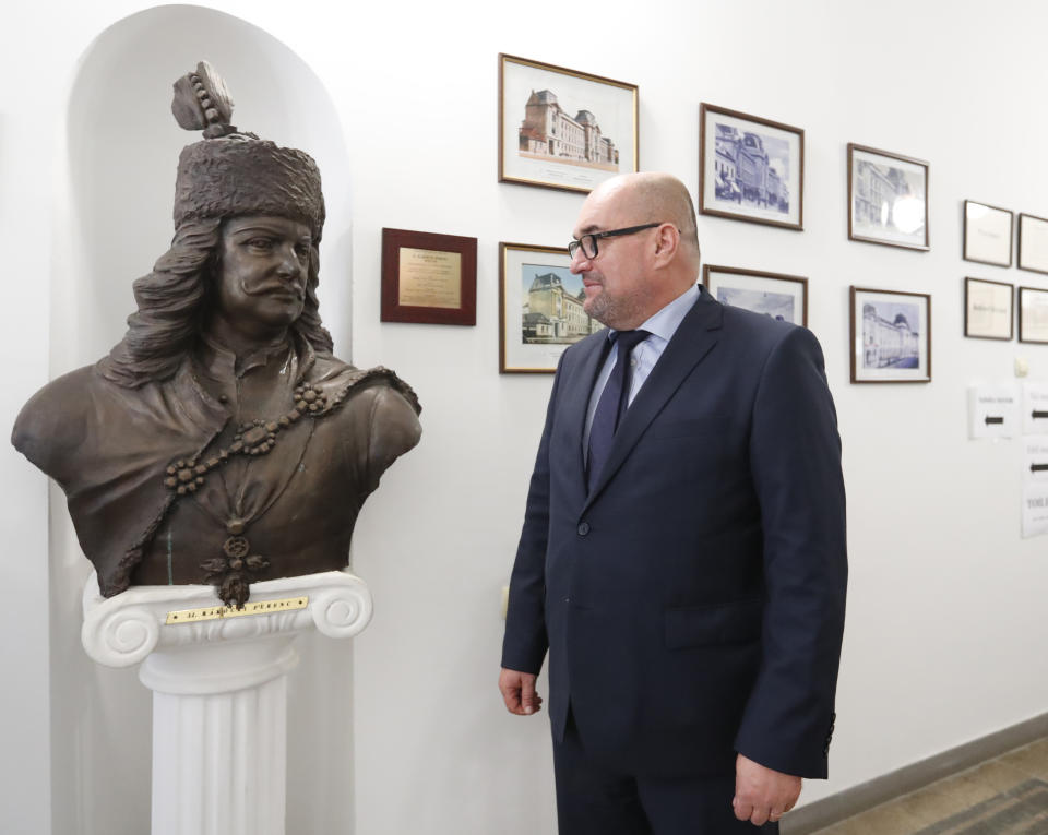 In this Friday, Oct. 19, 2018 photograph Laszlo Brenzovics, president of the Transcarpathian Hungarian Cultural Association stands next to a bust of Hungarian national hero Ferenc Rakoczy II, in Beherove, Ukraine. A new education law that could practically eliminate the use of Hungarian and other minority languages in schools after the 4th grade is just one of several issues threatening this community of 120,000 people. Many are worried that even as Ukraine strives to bring its laws and practices closer to European Union standards, its policies for minorities seem to be heading in a far more restrictive direction. (AP Photo/Laszlo Balogh)