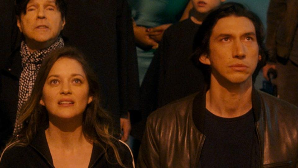 Marion Cotillard and Adam Driver look to the sky in a still from Annette.