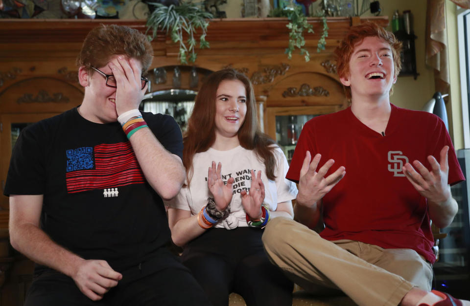 In this, Thursday, Feb. 7, 2019 photo, Ryan Deitsch, speaks as his sister Sam, center, and brother Matt, left, react during an interview with The Associated Press at their home in Parkland, Fla. The three siblings spent much of the past year spearheading the March for our Lives movement aimed at voter registration and gun control. (AP Photo/Wilfredo Lee)