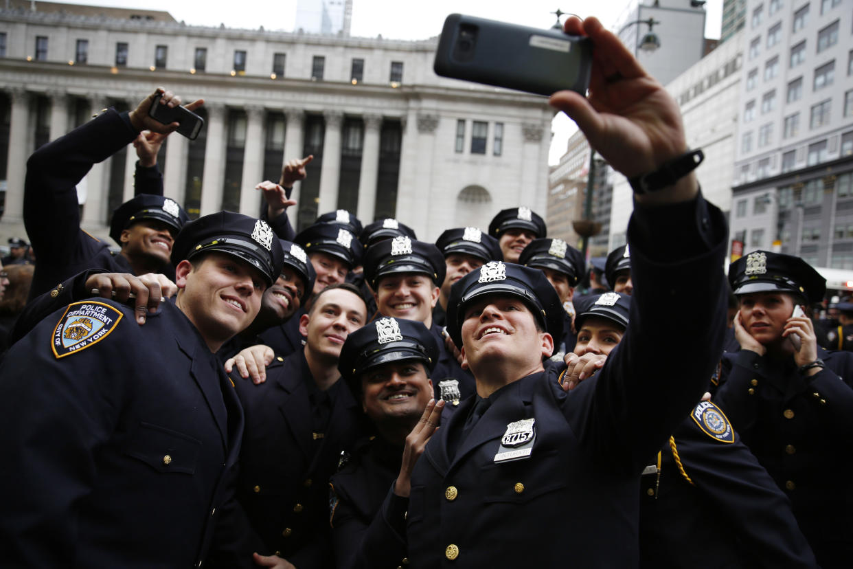 New NYPD Police Academy graduate Frank Cinturati, front, takes a selfie with his company after their graduation ceremony. Of approximately a score of graduates, two appear to be of color.