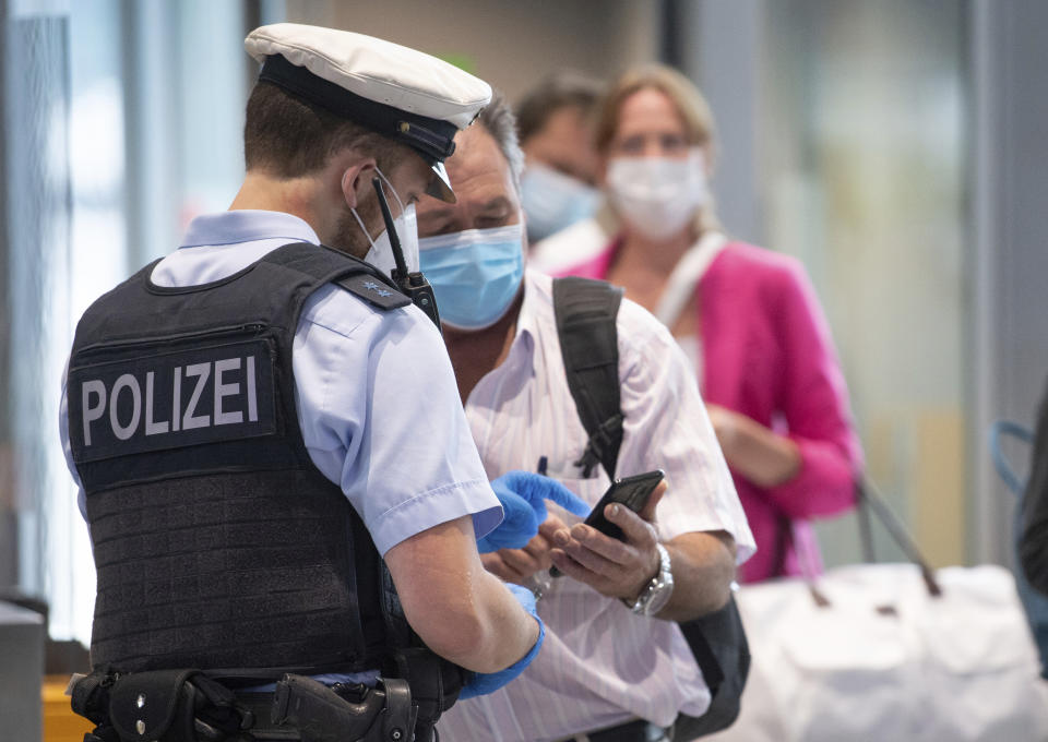 Federal police officers check passengers arriving aboard a flight from Portugal, at Frankfurt airport Tuesday June 29, 2021. As of Tuesday, Portugal is being considered a virus variant area, and people arriving in Germany must go into quarantine. (Boris Roessler/dpa via AP)