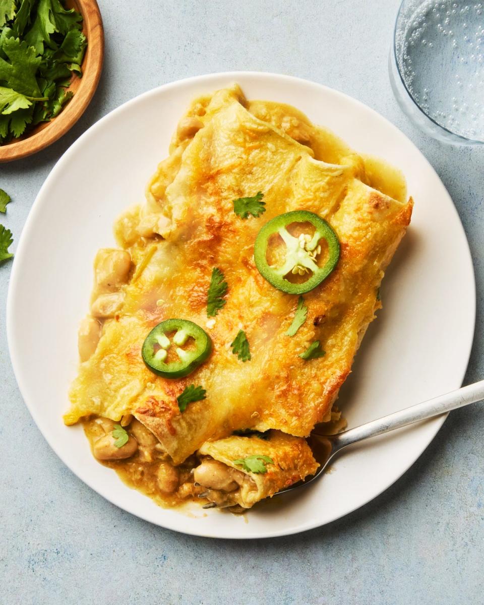 green chili white bean enchiladas on a white plate with a fork