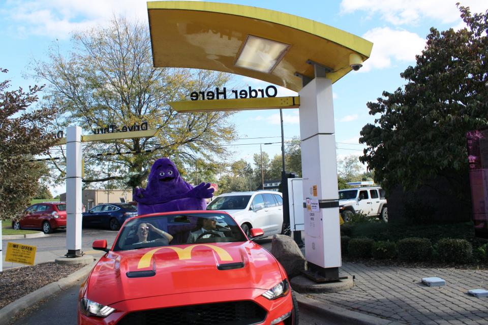Mike and Kathi Haller, newlyweds from Munich, Germany, enter drive-thru in a McDonald's Ford Mustang, accompanied by Grimace, iconic character, following wedding ceremony