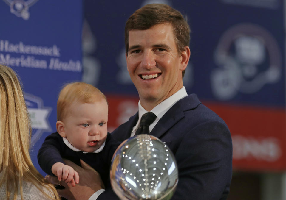 New York Giants NFL football quarterback Eli Manning holds his son Charles after announcing his retirement on Friday, Jan. 24, 2020, in East Rutherford, N.J. (AP Photo/Adam Hunger)