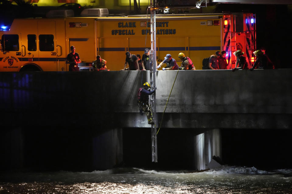 A Clark County Fire Department official climbs down a ladder to search for a man who was trapped in floodwaters in a flood channel Friday, Sept. 1, 2023, in Las Vegas. (AP Photo/John Locher)