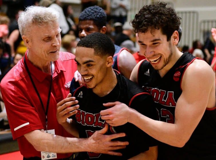 Biola University coach Dave Holmquist celebrates with players during a game.