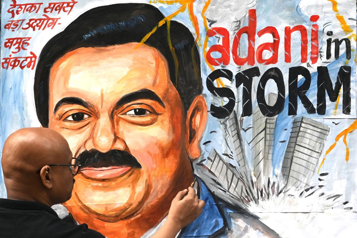Art school teacher Sagar Kambli gives final touches to a painting of Indian businessman Gautam Adani highlighting the ongoing crisis of the Adani group in Mumbai on February 3, 2023.