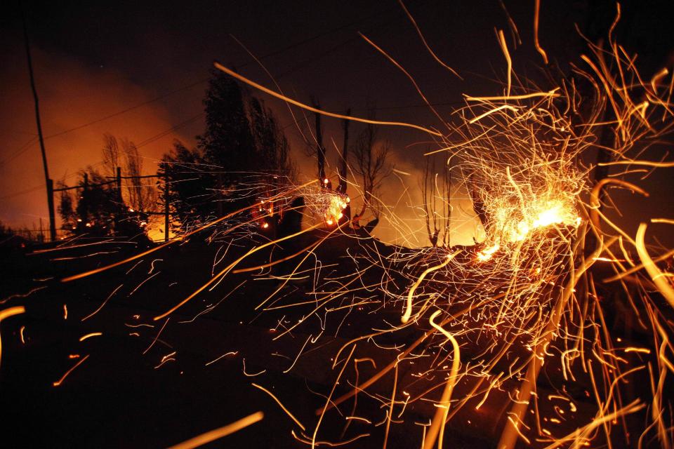 Sparks fly carried by the wind as a large forest fire reaches urban areas in Valparaiso, Chile, Sunday April 13, 2014. Authorities say the fires have destroyed hundreds of homes, forced the evacuation of thousands and claimed the lives of at least seven people. ( AP Photo/ Luis Hidalgo)