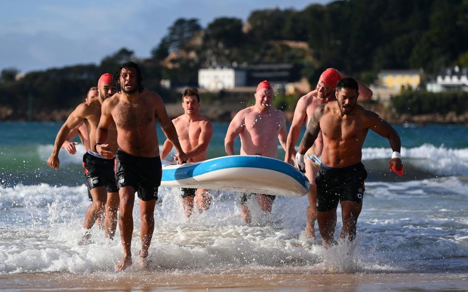 Lewis Ludlam of England and Manu Tuilagi of England lead their board onto shore during the England Rugby training camp on October 27, 2021 in St Brelade, Jersey. - GETTY IMAGES