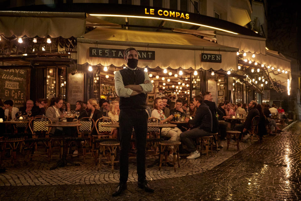 PARIS, FRANCE - SEPTEMBER 23: A waiter stands outside a busy terrace as Parisians relax as the French Government announced that from Monday all bars and cafes in Paris will be made to shut at 10pm as part of a string of new measures to curb the spread of Covid-19 in France on September 23, 2020 in Paris, France. With the rise in Coronavirus cases in France at 204 per 100,000 inhabitants, the French Government have followed other governments in introducing new restrictions aimed at reducing the spread of Covid-19 whilst avoiding another national lockdown. In large cities, including Paris, gatherings will be limited to ten people in public spaces, bars to close at 10 p.m., local and student parties will be prohibited. (Photo by Kiran Ridley/Getty Images)