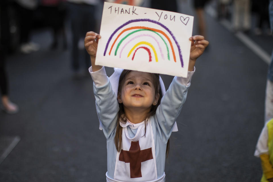 Image: Maria Sole, 4, holds up a homemade sign thanking NHS staff at London's Chelsea & Westminster Hospital. (Dan Kitwood / Getty Images file)