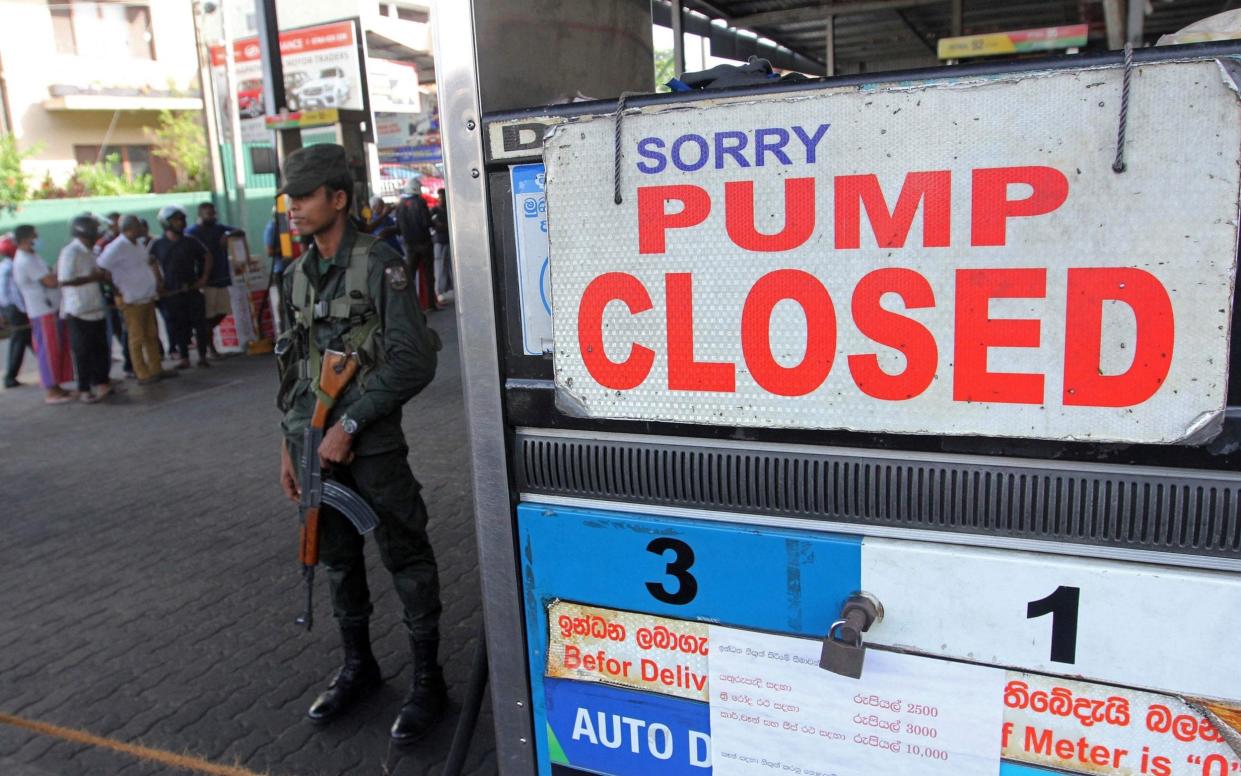 A Sri Lankan security guard stands outside a fuel station in Colombo that has run out of petrol - AFP