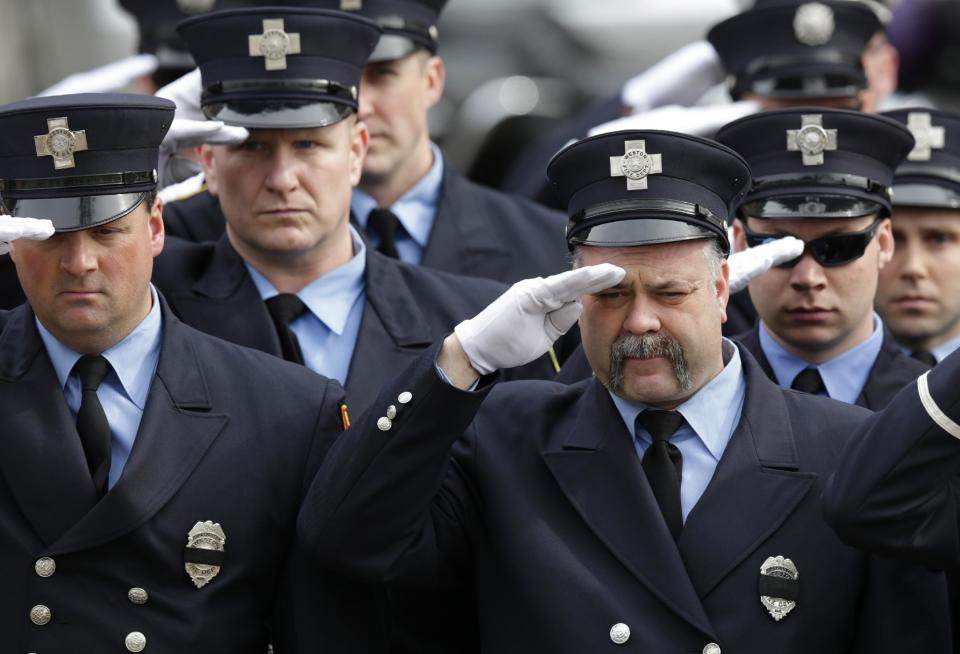 Firefighters salute as the funeral procession of Boston Fire Lt. Edward Walsh arrives outside the Church of Saint Patrick in Watertown, Mass., Wednesday, April 2, 2014. Walsh and Boston Firefighter Michael Kennedy died after being trapped while battling a fire in Boston. (AP Photo/Charles Krupa)