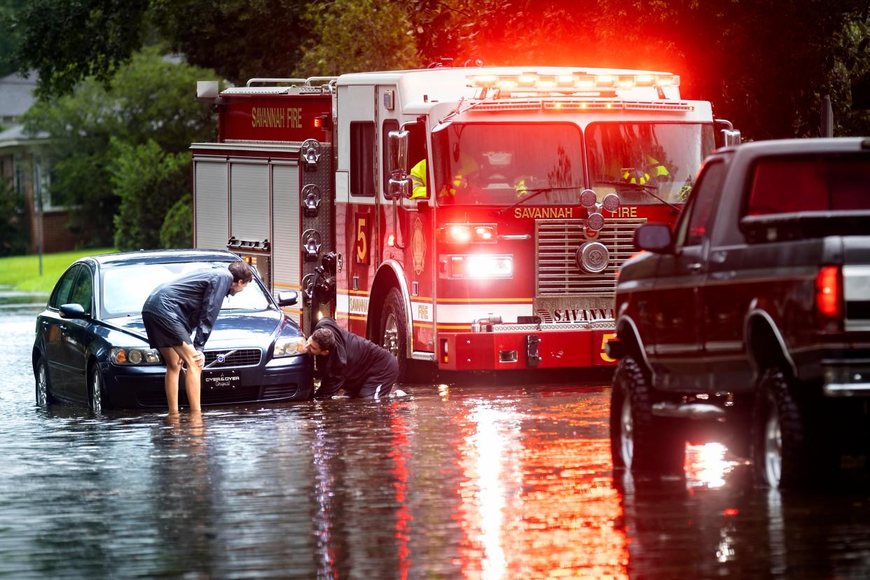 People attach a towline to a stranded vehicle on a flooded street in Savannah, Georgia (AP)