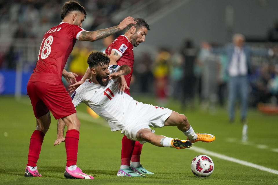 Iran's Ali Gholizadeh, center, duels for the ball with Syria's Jalil Elías, left, and Syria's Fahd Youssef during the Asian Cup Round of 16 soccer match between Iran and Syria, at Abdullah Bin Khalifa Stadium in Doha, Qatar, Wednesday, Jan. 31, 2024. (AP Photo/Aijaz Rahi)