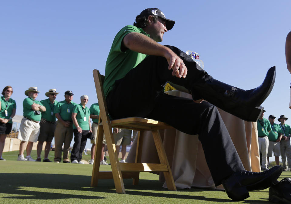 Steven Bowditch, of Australia, puts on the cowboy boots he was awarded for winning the Texas Open golf tournament, Sunday, March 30, 2014, in San Antonio. (AP Photo/Eric Gay)