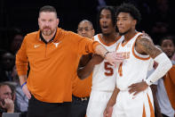 Texas' head coach Chris Beard, left, meets with Tyrese Hunter (4) and Marcus Carr (5) at the bench during the first half of the team's NCAA college basketball game against Illinois in the Jimmy V Classic, Tuesday, Dec. 6, 2022, in New York. (AP Photo/John Minchillo)