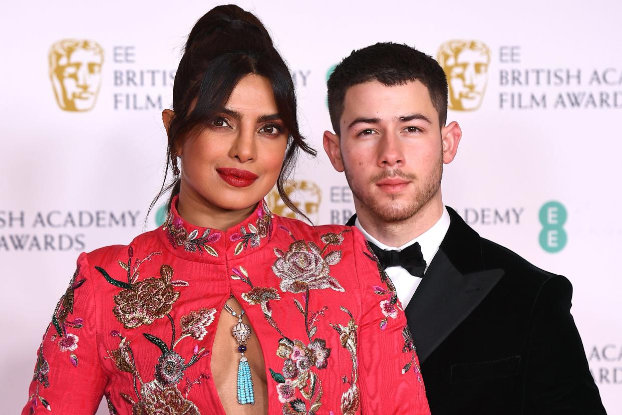 Priyanka Chopra in a floral dress standing next to Nick Jonas in a tux
