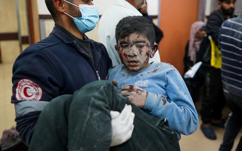 A medic carries a wounded Palestinian boy into the Al-Aqsa Martyrs Hospital in Deir al-Balah on March 19, 2024, following Israeli bombardment in the Nuseirat refugee camp in the central Gaza Strip