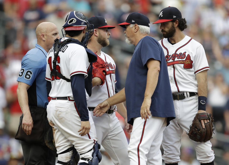 Atlanta Braves pitching coach Rick Kranitz, second from right, meets with pitcher A.J. Minter, center, in the ninth inning of a baseball game against the Washington Nationals, Saturday, July 9, 2022, in Atlanta. (AP Photo/Ben Margot)