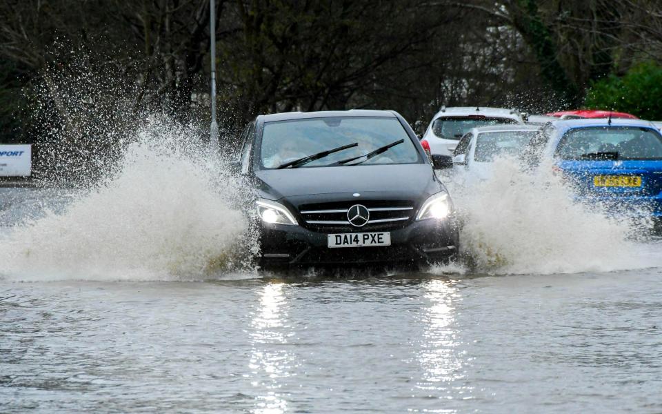 A car drives through deep floodwater on St Swithins Road at Bridport in Dorset