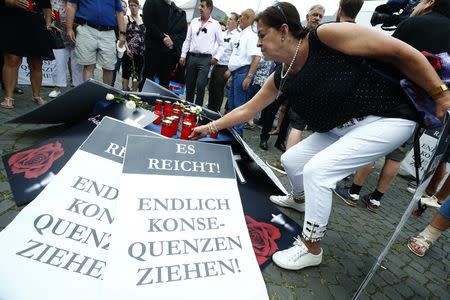 A woman places a candle during a demonstration called out by the Anti-immigration party Alternative for Germany (AfD) in Mainz, Germany, June 9, 2018, after a 20-year-old Iraqi man had admitted to the rape and murder of Susanna F., a 14-year-old German girl. Placard reads "Enough, finally draw the consequences". REUTERS/Ralph Orlowski