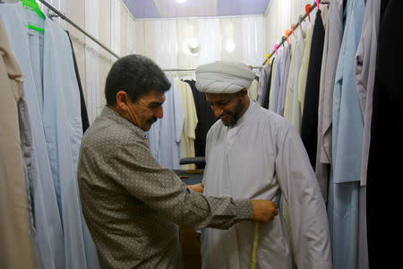 A tailor checks the size of a Shi'ite cleric's clothes in Najaf, south of Baghdad, Iraq, August 13, 2017. REUTERS/Abdullah Dhiaa Al-deen