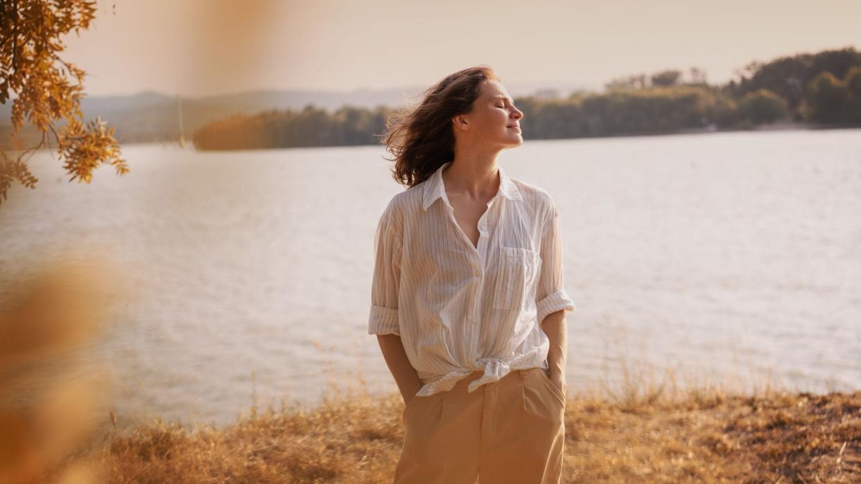 mujer relajada junto a un lago, al aire libre