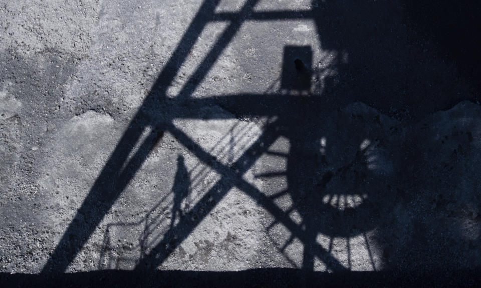 A man casts his shadow in the coal port of the Mehrum coal-fired power plant in the district of Peine in Hohenhameln, Germany, Wednesday, Jan. 15, 2020. Germany wants to gradually phase out the climate-damaging combustion of coal for electricity generation by 2038. ( Julian Stratenschulte/dpa via AP)