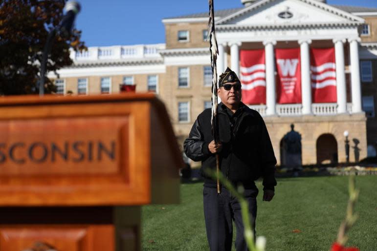 In recent years, Madison-area institutions including the University of Wisconsin-Madison have acknowledged that much of the land they occupy was taken from the Ho-Chunk Nation. On Nov. 5, 2021, the UW-Madison held a flag-raising ceremony adding the nation’s flag to the U.S. and Wisconsin flags flying above the campus. Here, Joseph White Eagle, American Legion Post 556 commander and member of the Ho-Chunk Nation, leads a color guard during the ceremony. (Coburn Dukehart / Wisconsin Watch)