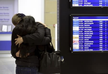 A couple embraces next to a flight information board at Pulkovo airport in St. Petersburg, Russia, October 31, 2015. REUTERS/Peter Kovalev