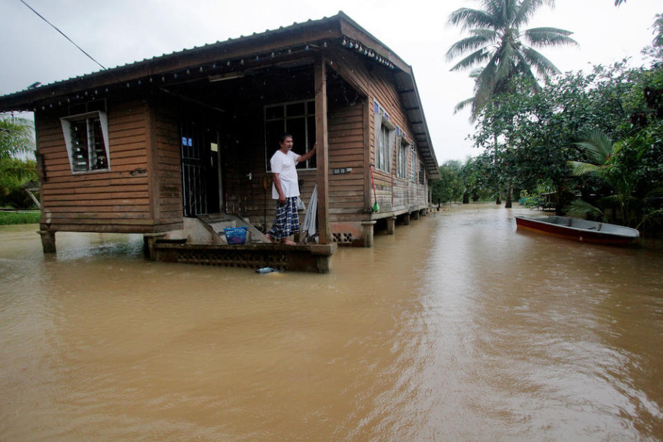 A resident of Kampung Gudang Rasau in Pahang looks on as flood waters surround his house. — Bernama pic