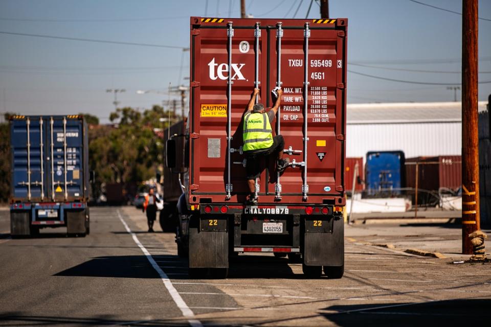 A truck driver checks his cargo as the Port of Los Angeles is set to begin operating around the clock.