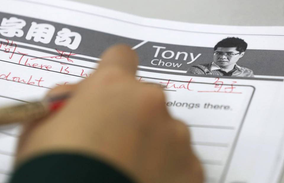 In this Dec. 9, 2013 photo, a student writes a note during the English grammar lesson by Tony Chow in a classroom of Modern Education in Hong Kong. The 30-year-old teaches English grammar to thousands of secondary school pupils, who attend his after-school lessons or watch video replays of them at Modern Education’s 14 branches. Chow is a celebrity tutor in Hong Kong, where there’s big money to be made offering extracurricular lessons to parents desperately seeking an edge for their children preparing for the city’s intense public entrance exam for university. (AP Photo/Kin Cheung)