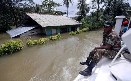An army officer sits on top of a moving armoured personnel carrier as a house is seen on a flooded road during a rescue mission in Bulathsinhala village, in Kalutara, Sri Lanka May 27, 2017. REUTERS/Dinuka Liyanawatte