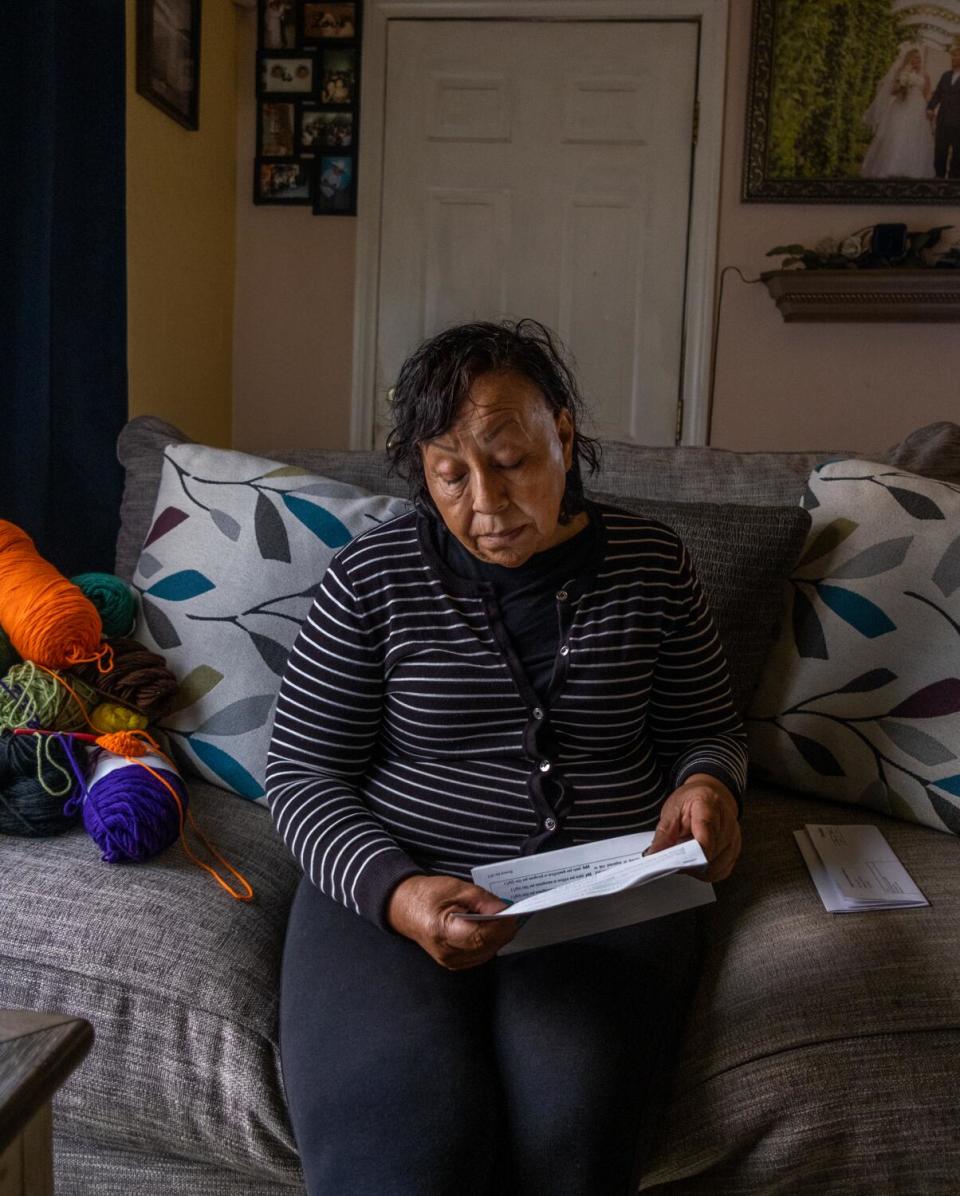 A woman sits on a couch reading a document.