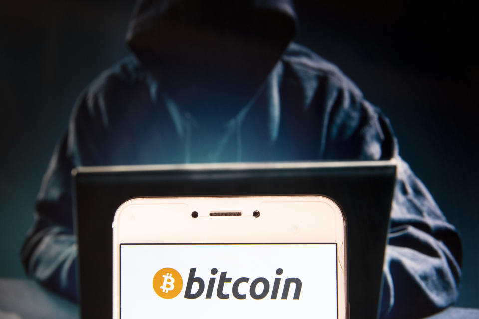 HONG KONG - 2018/11/22: In this photo illustration, the Cryptocurrency electronic cash Bitcoin logo is shown on an Android mobile device with a hacker figure in the background.  (Photo illustration by Miguel Candela/SOPA Images/LightRocket via Getty Images)