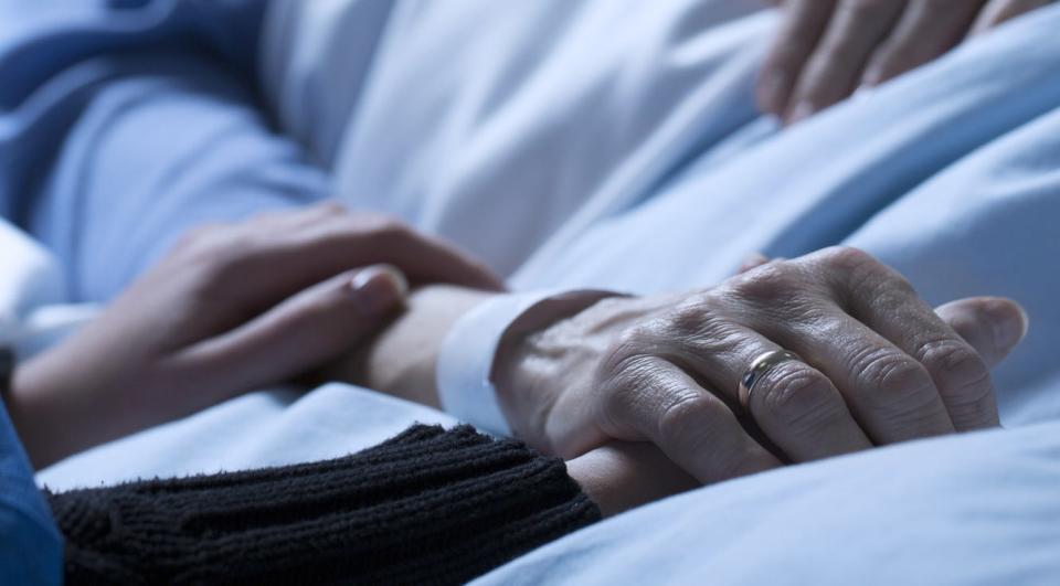 hand resting on the hand of someone in a hospital bed