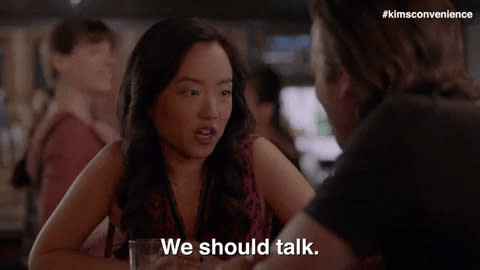 Two people at a table, one gesturing to initiate a conversation, subtitle reads "We should talk."