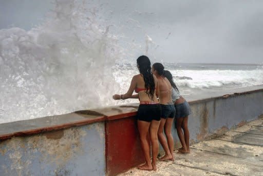 Tres jóvenes mirando las olas rompiendo en la localidad de Gibara, en la provincia de Holguín, en Cuba, el sábado 25 de agosto, con la llegada inminente de la tormenta tropical Isaac. (AFP | )